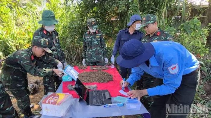 Cẩn thận lưu thông tin phục vụ giám định ADN tại nghĩa trang tạm thời chiến xã Nhuận Phú Tân. (Ảnh: HOÀNG TRUNG)