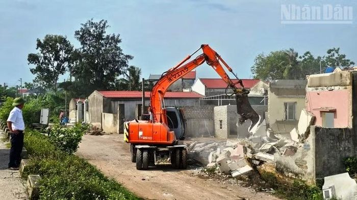 Nhân lực cùng phương tiện cơ giới hỗ trợ hộ dân tháo dỡ công trình trên đất, bảo đảm bàn giao mặt bằng sạch. (Ảnh: MAI LUẬN)