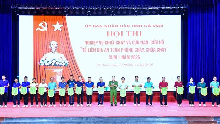 Đại tá Trần Văn Thi, Phó Giám đốc Công an tỉnh Cà Mau, Trưởng Ban Tổ chức hội thi (đứng giữa) trao cờ lưu niệm cho các đội tham gia cuộc. (Ảnh: Hữu Đệ)