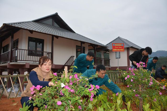  Người dân và dân quân thôn Làng Nủ chăm vườn hoa xung quanh những ngôi nhà tái định cư trên đỉnh đồi Sim. 