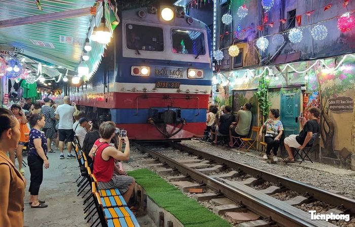 Du khách ngồi sát đường tàu quay video, chụp ảnh.