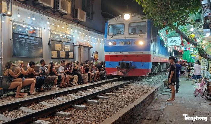 Rất đông người ngồi sát đường tàu quay video khi tàu chạy về Ga Hà Nội.