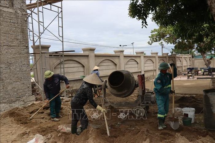 Tại trường Tiểu học Cẩm Quang, công nhân làm việc liên tục để hoàn thành các hạng mục phụ trợ như sân trường, tường rào đúng tiến độ.