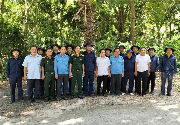 Lãnh đạo Bộ Chỉ huy Quân sự tỉnh An Giang và Đảng ủy xã Tri Tôn chụp ảnh lưu niệm cùng cán bộ, chiến sĩ Đội K93 đang làm nhiệm vụ tìm kiếm, quy tập hài cốt liệt sĩ. Ảnh: TTXVN phát