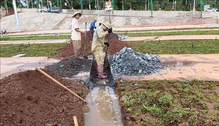 Công nhân cắt bê tông để tạo mương thoát nước. Ảnh: Hưng Thịnh/TTXVN