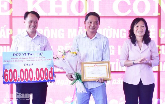 Lãnh đạo xã Mỹ Đức nhận bảng tượng trưng kinh phí tài trợ nâng cấp đường chùa Ông và tặng hoa tri ân đại diện đơn vị tài trợ.