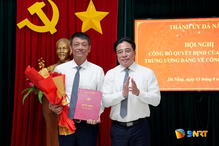 Phó Bí thư Thường trực Thành ủy Nguyễn Khắc Toàn (bên phải) trao quyết định và tặng hoa chúc mừng ông Nguyễn Hà Nam. Ảnh: T.CÔNG