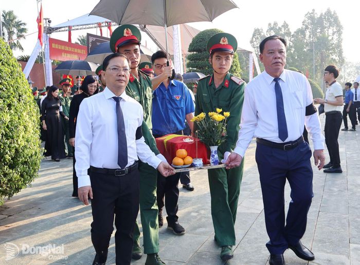 Phó Bí thư Thành ủy Võ Tấn Đức và Ủy viên Ban Thường vụ Thành ủy, Phó Chủ tịch Thường trực Ủy ban MTTQ Việt Nam thành phố Hà Anh Dũng thực hiện di quách hài cốt liệt sĩ về nơi an táng. Ảnh: Nguyệt Hà