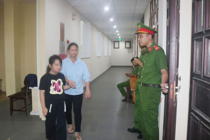 Chiến sĩ công an mở cửa phòng xét xử, bé Q.T dẫn mẹ vào khi phiên xét xử đang diễn ra