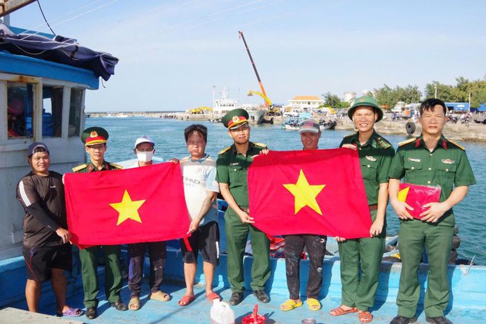 Cán bộ, chiến sĩ các đơn vị lực lượng vũ trang phối hợp tặng cờ Tổ quốc cho ngư dân Đặc khu Phú Quý