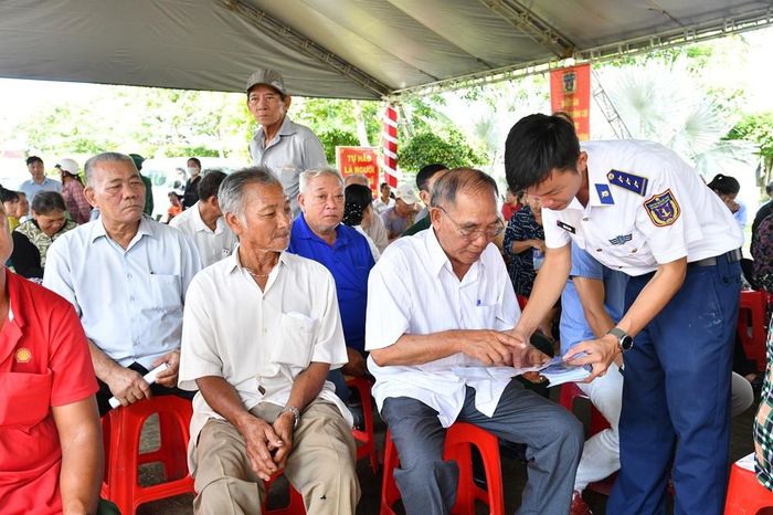 Cán bộ Bộ Tư lệnh Vùng Cảnh sát biển 4 phát tờ rơi, hướng dẫn bà con ngư dân quét mã QR tra cứu các quy định pháp luật. Ảnh: Đức Thái