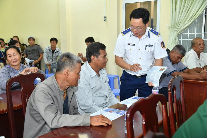 Cán bộ Bộ Tư lệnh Vùng Cảnh sát biển 4 phát tờ rơi tuyên truyền cho bà con ngư dân về chống khai thác IUU. Ảnh: Đức Thái