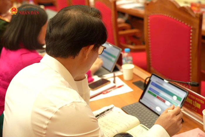 Các đại biểu xem xét, nghiên cứu các nghị quyết kỳ họp thông qua phần mềm “Kỳ họp không giấy” tại kỳ họp. Ảnh: Nguyễn Ánh