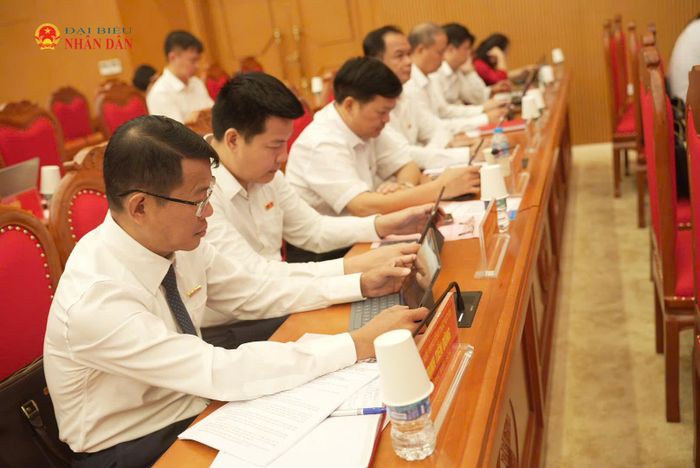 Các đại biểu biểu quyết thông qua nghị quyết tại kỳ họp bằng phần mềm “Kỳ họp không giấy”. Ảnh: Nguyễn Ánh