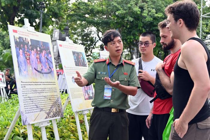 Cán bộ Công an Hà Nội giới thiệu với du khách nước ngoài về chuyên án ma túy thế kỷ Xiêng Phênh – Vũ Xuân Trường tại không gian triển lãm ảnh trên phố đi bộ.