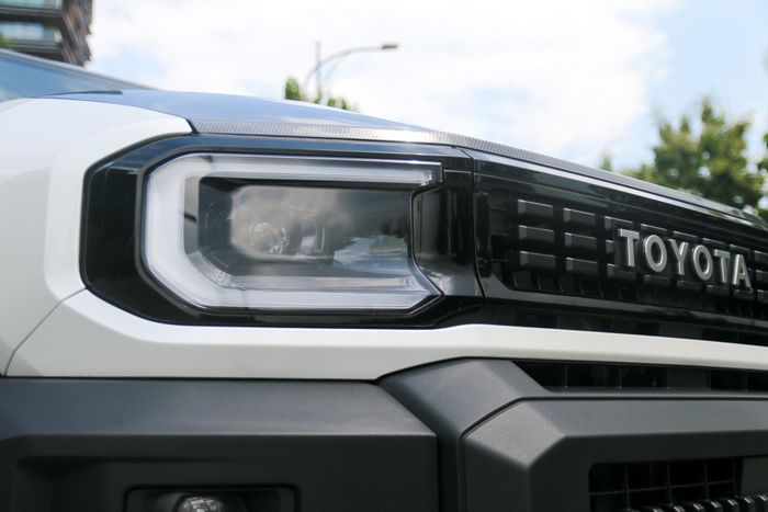 Nhìn từ chính diện, Toyota Land Cruiser FJ khá bệ vệ với cụm lưới tản nhiệt và hốc gió trung tâm kích thước lớn đều sơn đen, cản trước dày dặn cùng logo Toyota dạng chữ nổi bật. Cụm đèn chiếu sáng chính hình khối dạng LED Projector tích hợp đèn chạy ban ngày, có tính năng tự động bật tắt kèm cân bằng góc chiếu.
