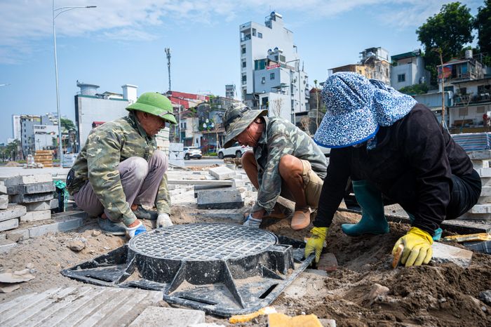 Trước cổng Bệnh viện Nhi Trung ương, đơn vị thi công đang khẩn trương thi công lát đá vỉa hè và lắp đặt hố ga.