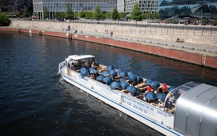 Khách du lịch che ô tránh nắng nóng khi đi thuyền ngắm cảnh tại Berlin, Đức. Ảnh: THX/TTXVN phát