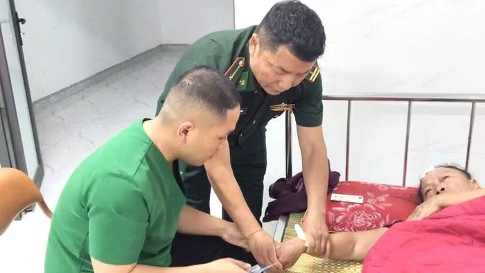Cán bộ, chiến sĩ Trạm Kiểm soát Biên phòng Keo Muông thực hiện sơ cứu ban đầu cho bà Tếnh Thị Mo, xã Lao Húng Phiêng Xa, huyện Xiềng Khọ, tỉnh Hủa Phăn, nước bạn Lào. (Ảnh: QUÀNG HÙNG)