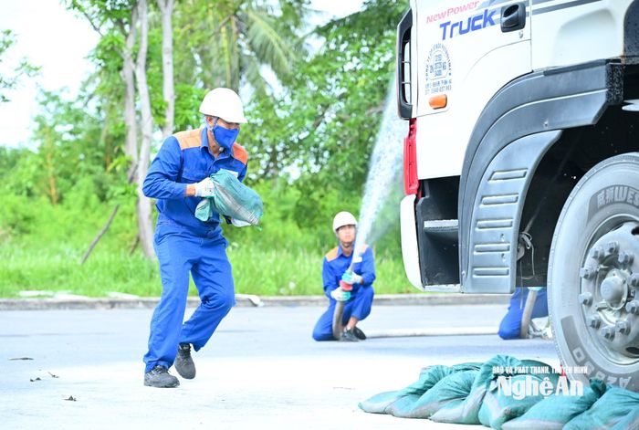 Công nhân Kho xăng dầu dùng bao cát ngăn dầu tràn ra môi trường xung quanh, hạn chế cháy lan. Ảnh: Thành Cường