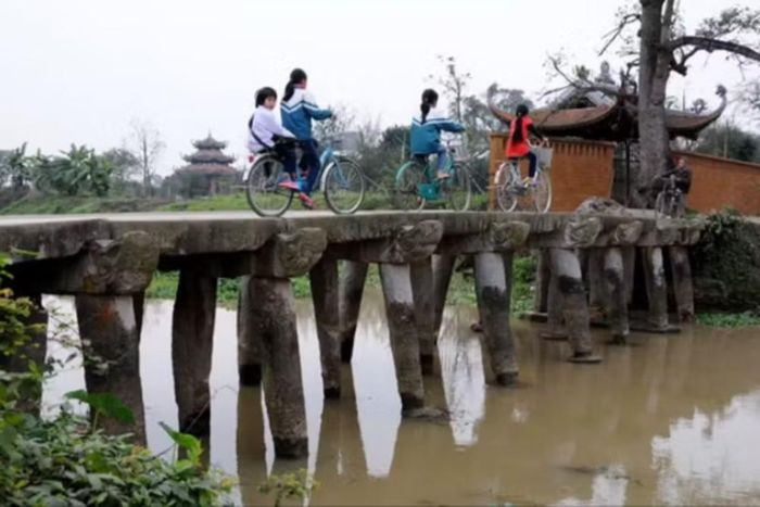 Cây cầu đá 9 nhịp đầu rồng soi bóng xuống dòng Nguyệt Đức tại làng Nôm. (Ảnh: Vietnam+)