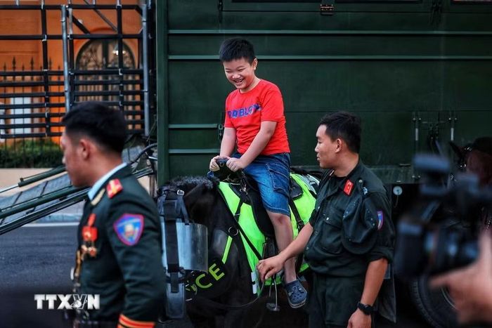 Niềm vui của một em nhỏ khi được trải nghiệm cưỡi ngựa dưới sự hướng dẫn, hỗ trợ của cán bộ, chiến sỹ Cảnh sát cơ động kỵ binh. (Ảnh: Phạm Tuấn Anh/TTXVN)