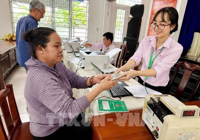 Nhân viên Phòng giao dịch Ngân hàng chính sách xã hội Châu Thành, tỉnh Đồng Tháp giải ngân món vay 100 triệu đồng cho người sau cai nghiện để chăn nuôi bò, xã Tân Hương. Ảnh: Hữu Chí - TTXVN