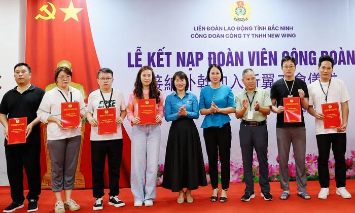 Đại diện Liên đoàn Lao động tỉnh và Công đoàn Công ty trách nhiệm hữu hạn Newwing Interconnect Technology trao quyết định kết nạp đoàn viên mới cho lao động người nước ngoài đang làm việc tại doanh nghiệp.