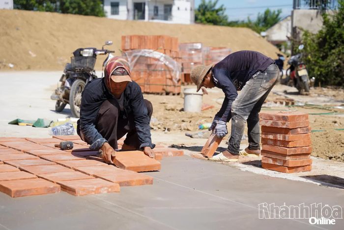 Nhóm công nhân thi công tuyến đường lát gạch thẻ trong khu vực di tích.