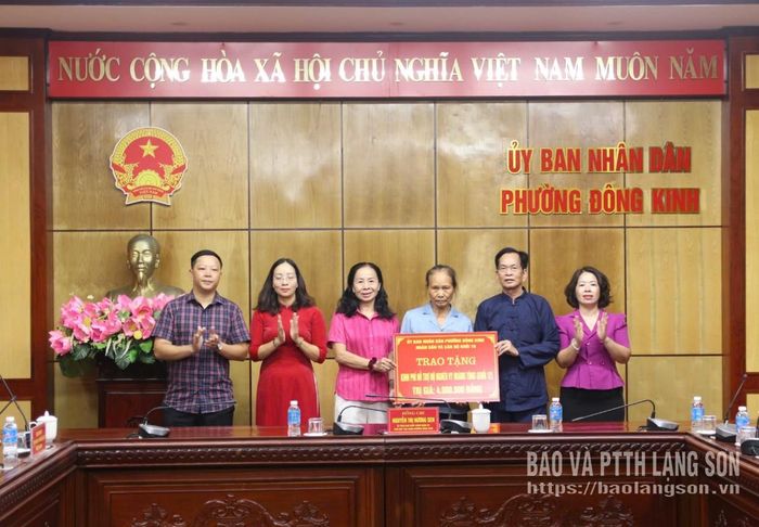 Lãnh đạo UBND phường Đông Kinh và đại diện khối 10 trao biểu trưng kinh phí hỗ trợ cho người giám hộ cháu Vy Hoàng Tùng