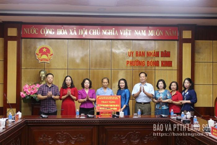 Lãnh đạo UBND phường Đông Kinh và đại diện khối Khòn Khuyêntrao biểu trưng kinh phí hỗ trợ cho người giám hộ cháu Vy Hoàng Tùng