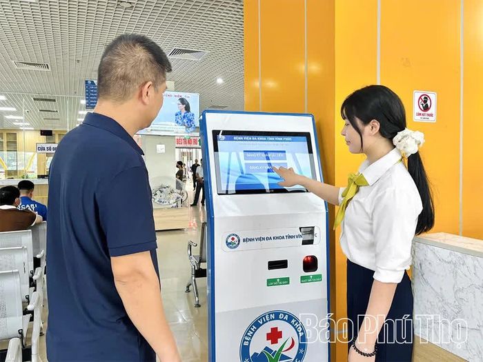 Nhân viên y tế hướng dẫn người dân lấy số tự động khi đến khám, chữa bệnh.