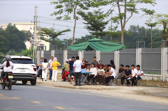 Nhiều phụ huynh nán lại bên ngoài khu vực thi, thấp thỏm chờ đợi trong thời tiết oi nóng, mong con hoàn thành bài thi thuận lợi.