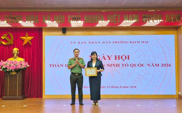 Đại diện Công an thành phố trao Giấy khen tặng cá nhân Phó Chủ tịch UBND phường Bạch Mai Nguyễn Thị Ngọc Anh. Ảnh: PV