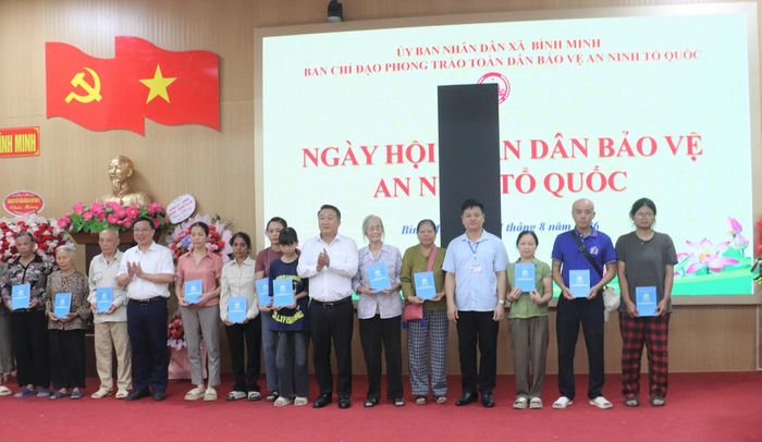 Lãnh đạo xã Bình Minh trao tặng các phần quà ý nghĩa cho các hộ gia đình khó khăn trên địa bàn nhân Ngày hội toàn dân bảo vệ ATTQ. Ảnh Đ. Đạt