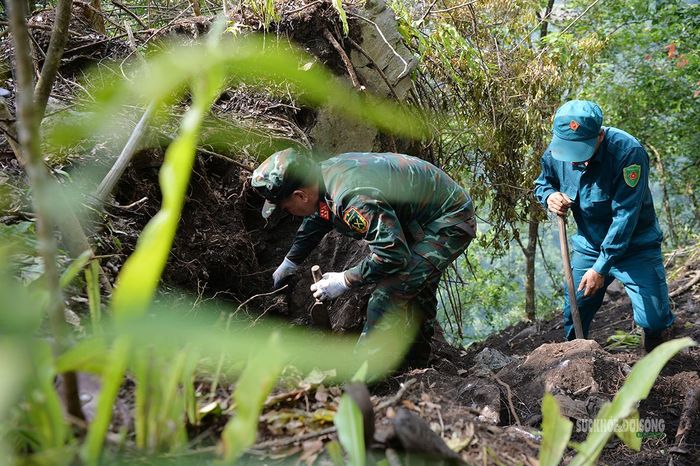 Bộ đội dùng dụng cụ thủ công đào tìm trong lớp đất đá giữa rừng. Ảnh: Tuấn An
