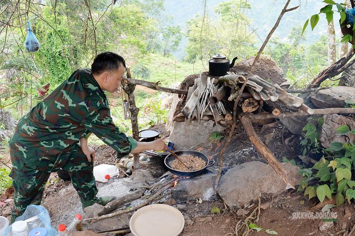 Thiếu tá Sầm Minh Phú chuẩn bị bữa trưa bên bếp lửa giữa rừng. Ảnh: Tuấn An