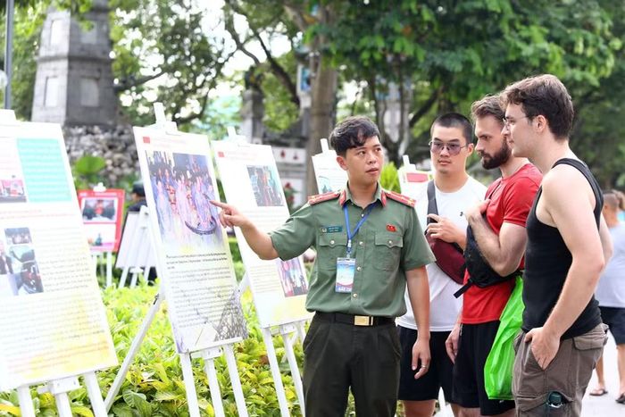 Chiến sĩ của Công an Hà Nội đang thuyết trình cho du khách quốc tế về một tấm ảnh