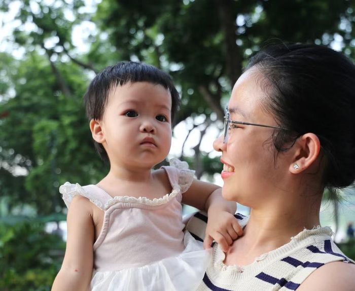 Một em bé được mẹ bế trên tay, chăm chú theo dõi