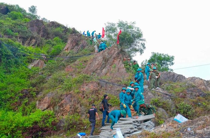 Những tấm bê tông nặng hơn 20kg được người dân chuyền tay qua từng đoạn dốc để đưa lên khu vực thi công. Ảnh: Hà Huệ