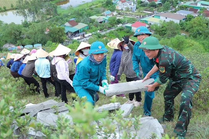 Cán bộ, chiến sĩ và người dân xã Lam Thành chung tay thay áo mới cho công trình lịch sử. (Ảnh: Hà Huệ)