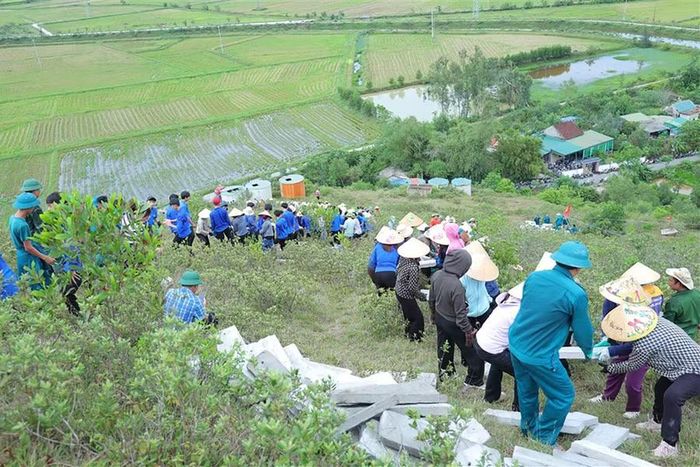 Từng tốp người nối tiếp nhau, chuyền tay các tấm bê tông từ chân núi lên khu vực thi công. (Ảnh: Hà Huệ)