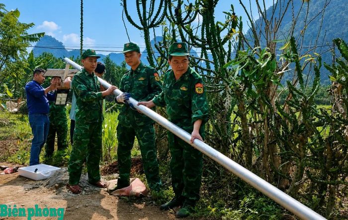 Cán bộ, chiến sĩ Đồn Biên phòng Đức Long, Bộ đội Biên phòng Cao Bằng và nhân dân địa phương lắp đặt đèn năng lượng mặt trời chiếu sáng tại khu dân cư biên giới. Ảnh: Quốc Sơn