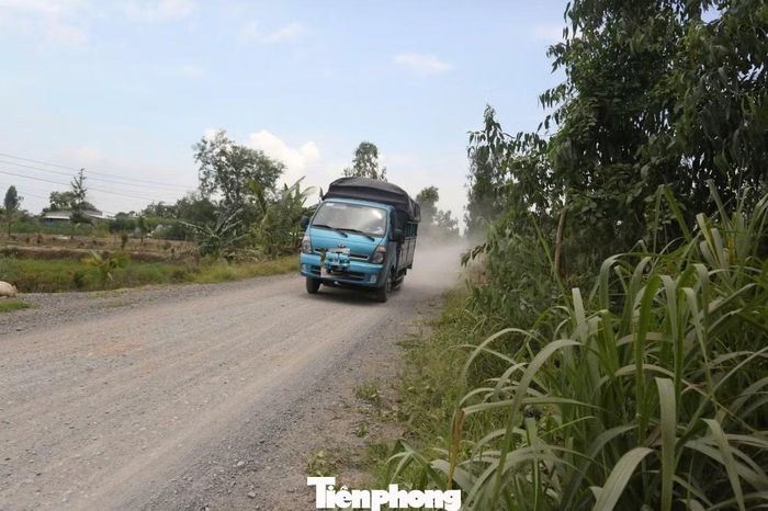 Mỗi lượt ô tô chạy qua, bụi từ mặt đường bị cuốn lên mù mịt, ảnh hưởng đến cuộc sống người dân. Ảnh: Nguyễn Tiến
