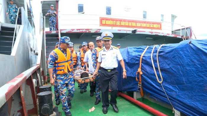 Cán bộ, chiến sĩ và lực lượng quân y đưa ngư dân Nguyễn Đức Quốc từ tàu TS16 lên bờ.