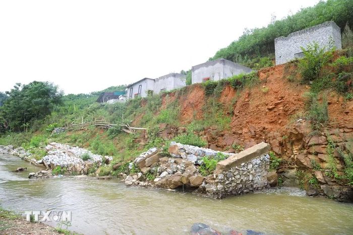 Bờ kè dài hàng chục mét bị lũ ống, lũ quét gây xói lở, đổ sập khiến nhiều ngôi nhà sinh sống phía trên bị đe dọa nghiêm trọng. (Ảnh: Xuân Tiến/TTXVN)