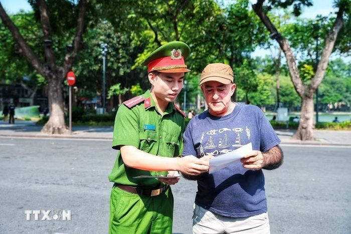 Cán bộ Công an giới thiệu cho một du khách nước ngoài tìm hiểu thông tin về Kiosk “Trạm Cảnh sát thông minh”, góp phần giúp người nước ngoài tiếp cận thuận tiện hơn với các dịch vụ hỗ trợ của lực lượng Công an. (Ảnh: Phạm Tuấn Anh/TTXVN)