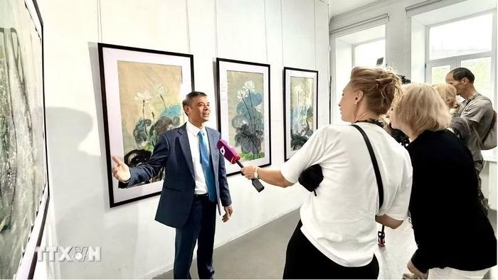 Họa sỹ Ngô Đức Hoàng giới thiệu tác phẩm. (Ảnh: TTXVN phát)