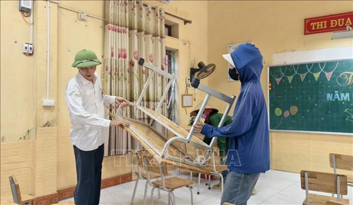Các thầy, cô giáo Trường Tiểu học Phú Hòa sắp xếp bàn ghế tại nơi học tạm chuẩn bị năm học mới. Ảnh: Thái Hùng/TTXVN