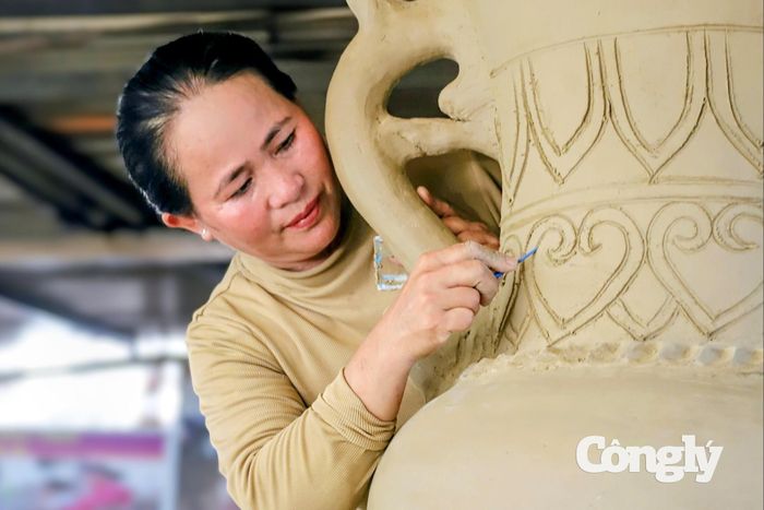 Chị Mỹ Xinh tạo hoa văn cho cặp bình gốm cao trên 2,2 mét trước khi chuyển vào lò nung.